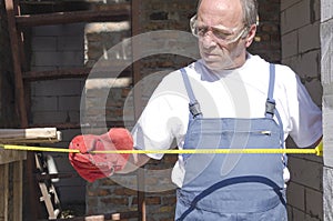 Construction worker using professional measuring tape to measure the distance between two walls.Laborer at work