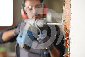 Construction worker using a rotary hammer to wreck a wall