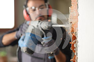 Construction worker using a rotary hammer to wreck a wall photo