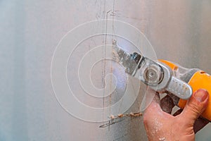 Construction worker using a sawsall tool to cut drywall a wall down to a diy house renovation