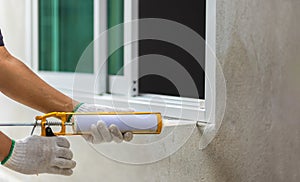 Construction worker using silicone sealant caulk the outside window frame
