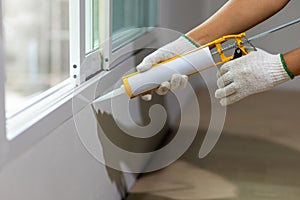 Construction worker using silicone sealant caulk the outside window frame