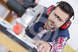 Construction worker using slider compound mitre saw