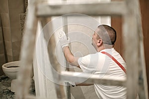 Construction worker using spirit level at home interior