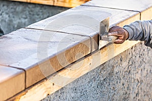 Construction Worker Using Stainless Steel Edger On Wet Cement Forming Coping Around New Pool