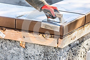 Construction Worker Using Stainless Steel Edger On Wet Cement Forming Coping Around New Pool