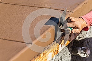 Construction Worker Using Stainless Steel Edger On Wet Cement Forming Coping Around New Pool