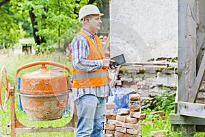 Construction worker using tablet PC near concrete mixer