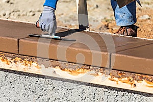 Construction Worker Using Trowel On Wet Cement Forming Coping Around New Pool