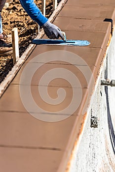 Construction Worker Using Trowel On Wet Cement Forming Coping Around New Pool