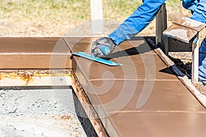 Construction Worker Using Trowel On Wet Cement Forming Coping Around New Pool