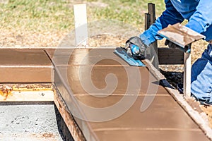 Construction Worker Using Trowel On Wet Cement Forming Coping Around New Pool