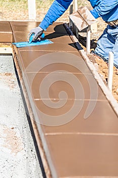 Construction Worker Using Trowel On Wet Cement Forming Coping Around New Pool