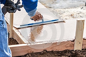 Construction Worker Using Trowel On Wet Cement Forming Coping Around New Pool