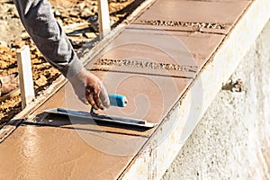 Laborer Using Trowel On Wet Cement Forming Coping Around New Pool