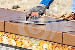 Construction Worker Using Trowel On Wet Cement Forming Coping Around New Pool