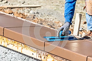 Construction Worker Using Trowel On Wet Cement Forming Coping Around New Pool