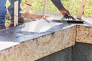 Construction Worker Using Wood Trowel On Wet Cement Forming Coping Around New Pool