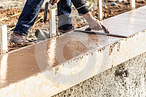 Construction Worker Using Wood Trowel On Wet Cement Forming Coping Around New Pool