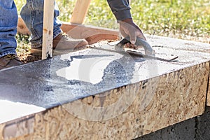 Construction Worker Using Wood Trowel On Wet Cement Forming Coping Around New Pool