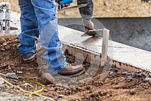 Construction Worker Using Wood Trowel On Wet Cement Forming Coping Around New Pool