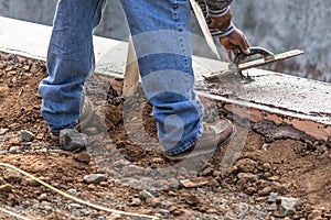 Construction Worker Using Wood Trowel On Wet Cement Forming Coping Around New Pool