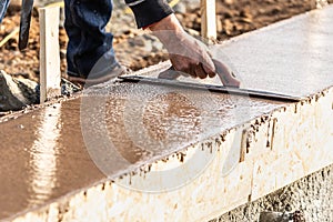 Construction Worker Using Wood Trowel On Wet Cement Forming Coping Around New Pool