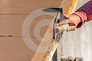 Construction Worker Using Wood Trowel On Wet Cement Forming Coping Around New Pool