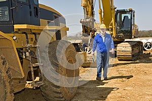 Construction Worker Walking Along Equipment