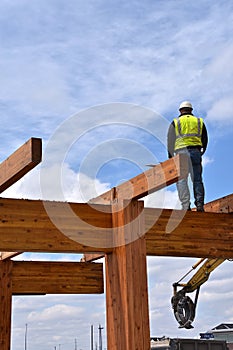 Construction worker walks on beams of a wood building