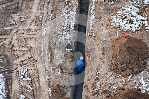 Construction worker walks in trench at the site. Top view