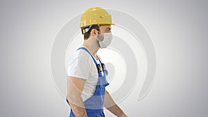 Construction worker wearing a hardhat and mask walking on gradient background.