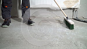 Construction worker sweeping the floor after renovation work.