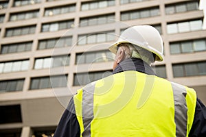 Construction worker wearing white safety helmet and high visibility vest.