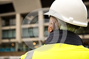 Construction worker wearing white safety helmet and high visibility vest.