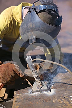 Construction worker welder wearing welding safety equipment glove helmet commencing welding hot work on industrial safety lifting