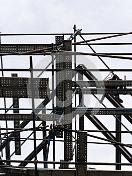 The construction worker is working on the high scaffolding