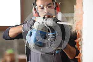 Construction worker wrecking wall using rotary hammer