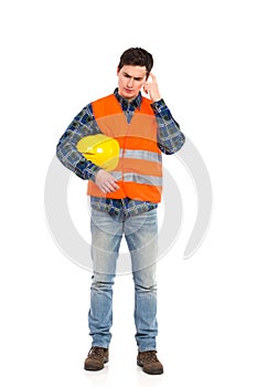 Construction worker in yellow helmet and orange waistcoat scratching head. photo