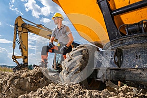 Construction Worker Resting Near Heavy Machinery During Sunny Day at Construction Site