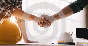 Construction workers, architects and engineers shake hands while working for teamwork and cooperation after completing an