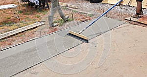 Construction workers brush freshly poured concrete with a broom brushing pattern