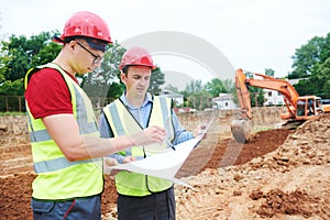 Construction workers on building area. Foreman with blueprint and surveyoor