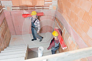 Construction workers carrying red pipes