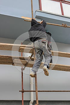 Construction workers climbs on scaffolding