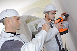 Construction workers drilling concrete wall
