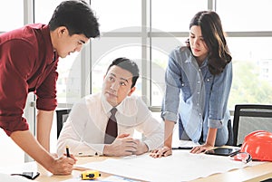 Construction workers , a female architect and two male engineers discussing about the project at office table indoor