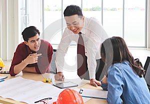 Construction workers , a female architect and two male engineers discussing about the project at office table indoor