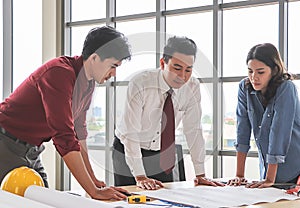 Construction workers , a female architect and two male engineers discussing about the project at office table indoor