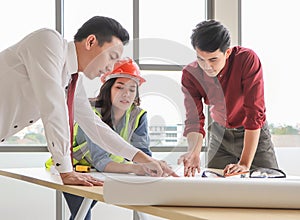 Construction workers , a female architect and two male engineers discussing about the project at office table indoor